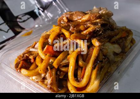 Japanisches Yaki Udon (gebratene Udon-Nudeln) in einem Tablett des lokalen Supermarkts. Es ist ein Rührgericht, das aus udon-Nudeln mit Sauce, Schweinefleisch und Gemüse besteht Stockfoto