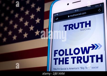 Kumamoto, JAPAN - Nov 2 2021 : TRUTH Social, SNS-Plattform wird von der Trump Media and Technology Group (TMTG) auf dem iPhone auf US-Flagge in dunkler Stimmung gestartet Stockfoto