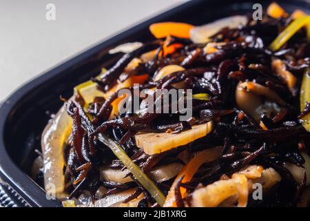 Nahaufnahme Japanischer gekochte Hijiki-Salat (Sargassum fusiforme, syn. Hizikia fusiformis), verkauft von japanischen lokalen Supermarkt. Hijiki ist ein braunes Meeresgemüse Stockfoto