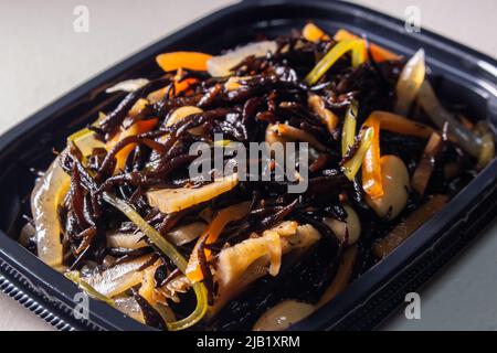 Nahaufnahme Japanischer gekochte Hijiki-Salat (Sargassum fusiforme, syn. Hizikia fusiformis), verkauft von japanischen lokalen Supermarkt. Hijiki ist ein braunes Meeresgemüse Stockfoto