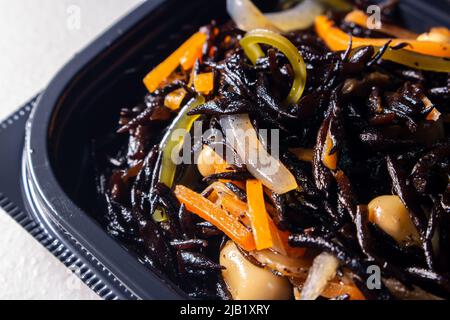 Nahaufnahme Japanischer gekochte Hijiki-Salat (Sargassum fusiforme, syn. Hizikia fusiformis), verkauft von japanischen lokalen Supermarkt. Hijiki ist ein braunes Meeresgemüse Stockfoto