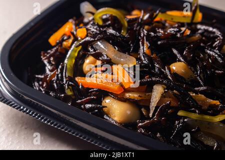 Nahaufnahme Japanischer gekochte Hijiki-Salat (Sargassum fusiforme, syn. Hizikia fusiformis), verkauft von japanischen lokalen Supermarkt. Hijiki ist ein braunes Meeresgemüse Stockfoto