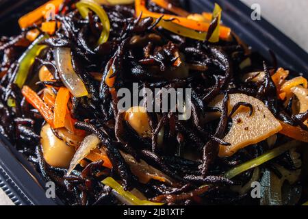 Nahaufnahme Japanischer gekochte Hijiki-Salat (Sargassum fusiforme, syn. Hizikia fusiformis), verkauft von japanischen lokalen Supermarkt. Hijiki ist ein braunes Meeresgemüse Stockfoto