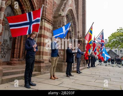 Fahnenträger halten die Flaggen Norwegens und Schottlands vor der St. Magnus Cathedral hoch, um den Norway Day im Stadtzentrum von Kirkwall, Orkney Islands, SCO, zu feiern. Stockfoto