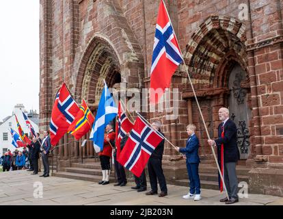Fahnenträger halten die Flaggen Norwegens und Schottlands vor der St. Magnus Cathedral hoch, um den Norway Day im Stadtzentrum von Kirkwall, Orkney Islands, SCO, zu feiern. Stockfoto