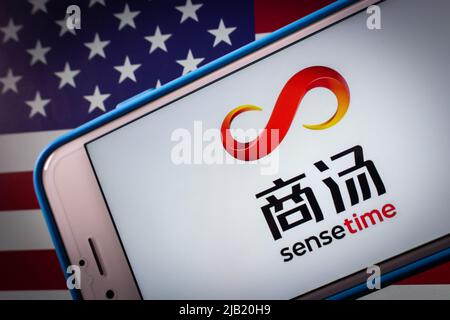 Kumamoto, JAPAN - Dez 14 2021 : Logo von SenseTime, einem führenden Softwareunternehmen für künstliche Intelligenz in Hongkong, auf dem iPhone auf US-Flagge in dunkler Stimmung Stockfoto