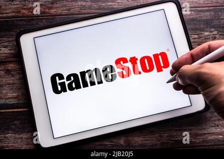 Kumamoto, JAPAN - Jan 21 2022 : Logo von GameStop Corp., einem US-amerikanischen Einzelhändler für Videospiele, Unterhaltungselektronik und Gaming-Waren auf Tablets. Der Mann hält den Stift Stockfoto