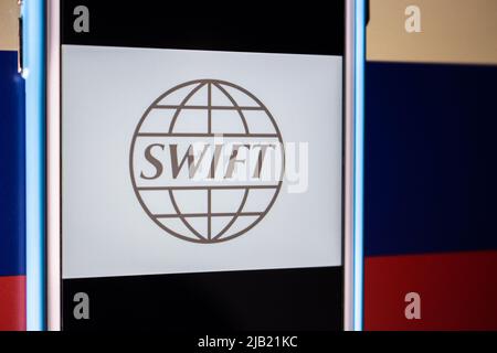 Logo von SWIFT (The Society for Worldwide Interbank Financial Telecommunication) auf dem iPhone auf russischer Flagge. Sanktionen für Ukraine Invasion Konzept Stockfoto
