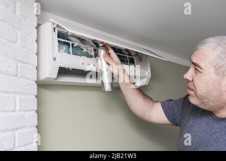 Reinigung eines schmutzigen und staubigen Klimaanlagenfilters im Haus. Männlich Entfernen eines staubigen Klimaanlagenfilters. Stockfoto