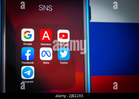 Beliebte Symbole für SNS- und IT-Unternehmen (Google, Alphabet Inc, YouTube, Facebook, Meta Platform, Twitter und Telegram) auf dem iPhone mit russischer Flagge in dunkler Stimmung Stockfoto