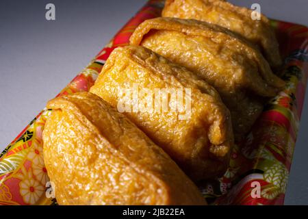 Nahaufnahme Inarizushi (Inari-Sushi oder Fuchsushi), eine Art Sushi, hergestellt aus einem Ball gewürzten Sushi-Reis, eingewickelt in aburazeit (ein Beutel gebraten Stockfoto