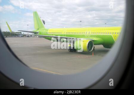 Blick aus dem Fenster des Flugzeugs auf den Flugplatz und das in der Nähe stehende Flugzeug. Selektiver Fokus. Urlaub, Reisekonzept. Stockfoto