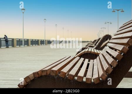 Sonnenliegen an einer leeren Meerpromenade im Vorgriff auf die Weihnachtszeit. Selektiver Fokus. Stockfoto