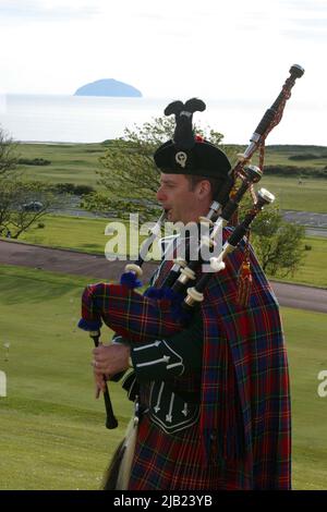 Turnberry Hotel, Ayrshire, Schottland, Großbritannien. Der schottische Piper im Higlhand-Kleid spielt vor dem Trump Turnberry Hotel, mit Ailsa Craig im Hintergrund Stockfoto