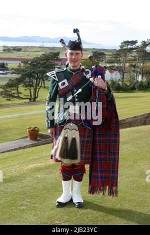 Turnberry Hotel, Ayrshire, Schottland, Großbritannien. Scottish Piper in Higlhand-Kleid spielt vor dem Trump Turnberry Hotel, mit der Isle of Arran im Hintergrund Stockfoto