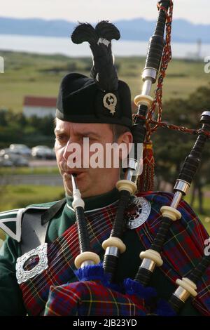 Turnberry Hotel, Ayrshire, Schottland, Großbritannien. Scottish Piper in Higlhand-Kleid spielt vor dem Trump Turnberry Hotel, mit der Isle of Arran im Hintergrund Stockfoto