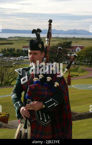 Turnberry Hotel, Ayrshire, Schottland, Großbritannien. Scottish Piper in Higlhand-Kleid spielt vor dem Trump Turnberry Hotel, mit der Isle of Arran im Hintergrund Stockfoto