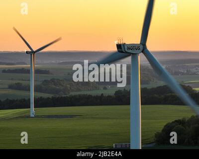 Aus der Vogelperspektive von Windmühlen in einer Gruppe von Landwirtschaftsbetrieben ein heller Sonnenuntergang. Grüne Umwelt und Windturbinenfarm. Stockfoto