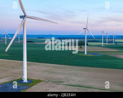 Luftaufnahme eines Windparks in einer üppigen Landschaft, die sich weit unter einem klaren Himmel erstreckt Stockfoto