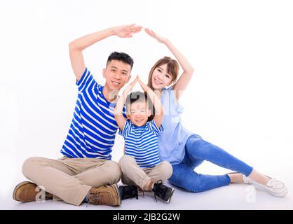 Glückliche Familie bildet Hausdach mit Händen zu Hause. Versicherungs- und Hauskonzept Stockfoto