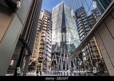 Ein Mann und eine Frau gehen entlang der Lime Street in der City of London mit dem Lloyd's of London Gebäude und dem Leadenhall Gebäude im Hintergrund, London, EC3 Stockfoto