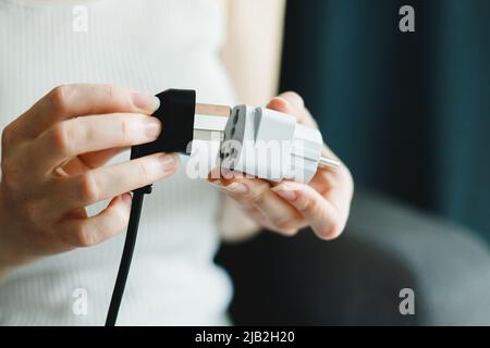 Woman applies universal European Plug Adapter International AU UK US to Euro. Steckerbuchse des Reiseadapters für elektrische Messungen Stockfoto