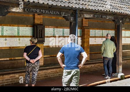 Menschen, die sich die Keramik-Gedenktafeln am Watts Memorial to Heroic Self-Sacrifice im Postman’s Park , London EC1 ansehen Stockfoto