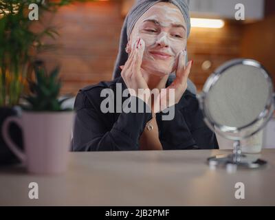 Genießen Sie makellose Haut . Friedliche Dame, die während der Eingriffe in der Küche mit dem Zustand ihrer Haut zufrieden war. Die schöne kaukasische Frau putzt Stockfoto