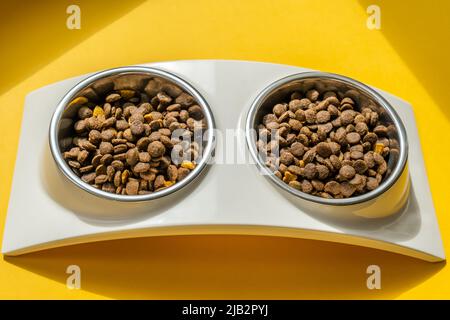 Kibble in PET-Schalen auf dem gelben Hintergrund Stockfoto
