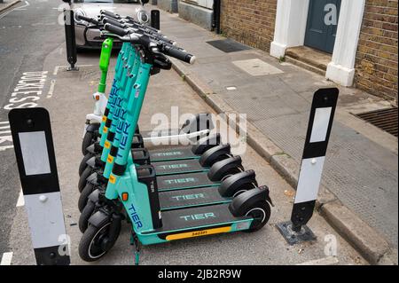 London, Großbritannien - 3. Mai 2022: Tier-Verleih-Scooter Reihen sich auf einer Straße in London an Stockfoto