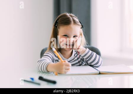 Niedliche kleine Mädchen Hausaufgaben machen, ein Buch zu lesen, Malvorlagen, schreiben und malen. Kinder malen. Kinder ziehen. Stockfoto