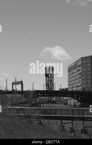 Eine sehr hohe Stahltraversenkonstruktion, die im Industrieviertel in Schwarz und Weiß steht. Stockfoto