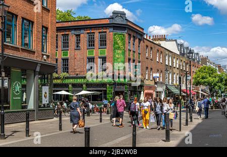 Leute, die die Sonne genießen und am Exmouth Arms auf dem Exmouth Market, Clerkenwell, London EC1, vorbeilaufen Stockfoto