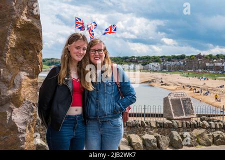 North Berwick, East Lothian, Schottland, Großbritannien, 2.. Juni 2022. Jubiläumsfeiern: Die Feierlichkeiten beginnen im Badeort. Im Bild: Die Teenagerin Jessica und ihre Mutter kommen mit Union Jack Haarbändern in den Wind, während sie im Urlaub die Küstenstadt mit Blick auf East Beach genießen Stockfoto