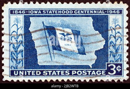 USA - UM 1946: Eine in den USA gedruckte Briefmarke, die anlässlich des 100. Jahrestages der Staatlichkeit von Iowa herausgegeben wurde, zeigt die Iowa State Flag und Map, um 1946. Stockfoto