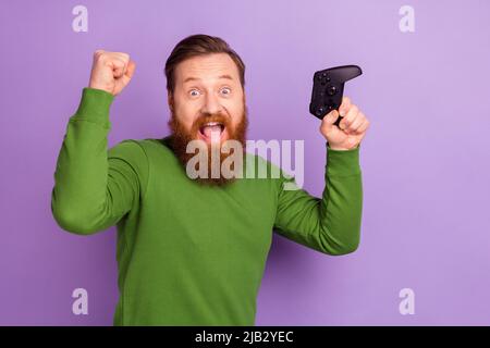 Foto von überglücklich ekstatischen jungen Mann aufgeregt, um Runde im Spiel halten playstation isoliert auf lila Hintergrund gewinnen Stockfoto
