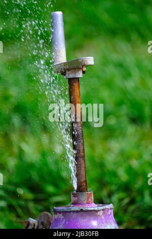 Sprinklerleitung mit undichter Armatur und austretendem Wasser und Sprühen durch Leck Stockfoto