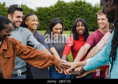 Junge, multiethnische Gruppe von Menschen, die ihre Hände im Freien stapeln - Konzept der Teamwork-Vielfalt und -Einheit Stockfoto