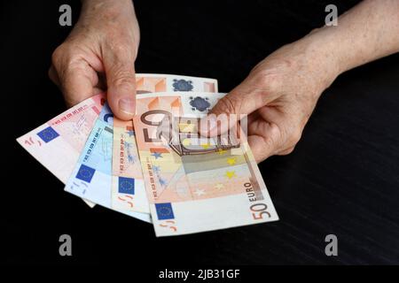 Ältere Frau mit Euro-Scheinen in faltigen Händen. Konzept der Pensionszahlungen, Einsparungen im Ruhestand, Rentner mit Geld Stockfoto