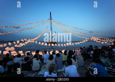 (220602) -- YOKOHAMA, 2. Juni 2022 (Xinhua) -- am Meer sitzen Menschen im Rinko Park, um auf das Feuerwerk während des Yokohama Port Opening Festivals in Yokohama, Japan, am 2. Juni 2022 zu warten. (Xinhua/Zhang Xiaoyu) Stockfoto