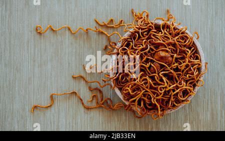 Blick in den hohen Winkel auf einen Teller mit Hühnchen-Yakisoba-Nudeln, auf einem Tisch mit beigefarbener Tischdecke oder Tischdecke Stockfoto
