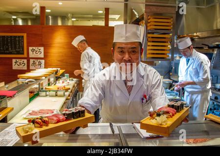 Ein Koch bietet abends in Tokio frisches Sushi an Stockfoto