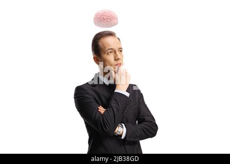 Nachdenklicher Geschäftsmann, der sein Kinn und sein Denken hält und ein Gehirn über seinem Kopf schwebt, isoliert auf weißem Hintergrund Stockfoto