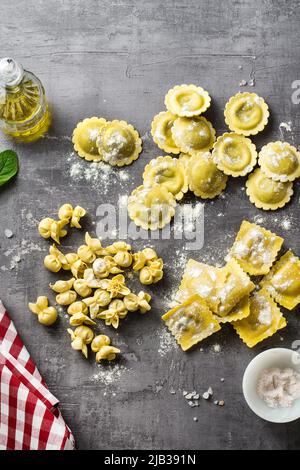 Verschiedene Arten von frischen rohen italienischen Ravioli auf dem Tisch mit Kochzutaten. Hausküche Stockfoto