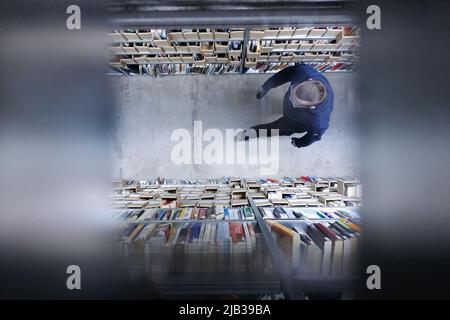 Leipzig, Deutschland. 24.. Februar 2022. Ein Mitarbeiter geht entrinken das Lager der Online-Versandfirma Momox, durch ein Gitter genommen. Quelle: Sebastian Willnow/dpa-Zentralbild/dpa/Alamy Live News Stockfoto