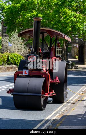 Rot-schwarzes, stationäres, schweres Dampffahrzeug, das am Straßenrand angehalten und geparkt wurde (L-Platte vorne) - Burley-in-Wharfedale, West Yorkshire, England, Großbritannien. Stockfoto
