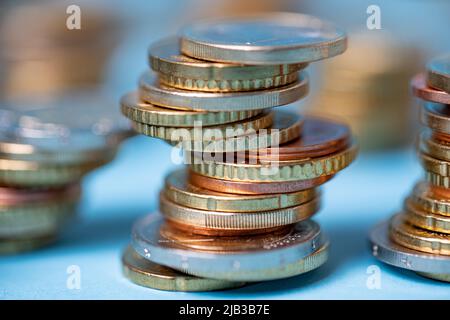 Euro-Münzen zu Türmen aufgeschichtet. Münzen auf blauem Hintergrund. EUR-Währung aus der Europäischen Union Stockfoto
