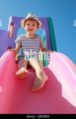 Glückliches Kind spielt mit rosa Folie auf blauem Himmel Hintergrund. Spielzeitkonzept Stockfoto