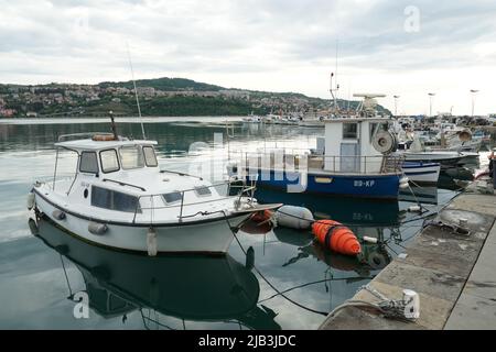 Mehrere Fischerboote vertäuten im Hafen in der Stadt Koper in der Nähe des Stadtzentrums. Um die Schiffe herum schweben Bojen. Stockfoto