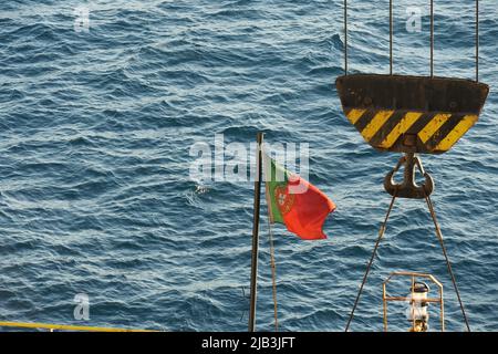 Flagge Portugals auf schwarzem Mast im hinteren oder hinteren Teil des Containerschiffes. Stockfoto